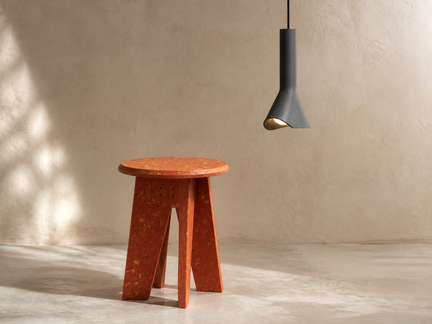 Orange recycled-plastic BENTU “#” stool beneath a dark grey BENTU RU concrete pendant lamp