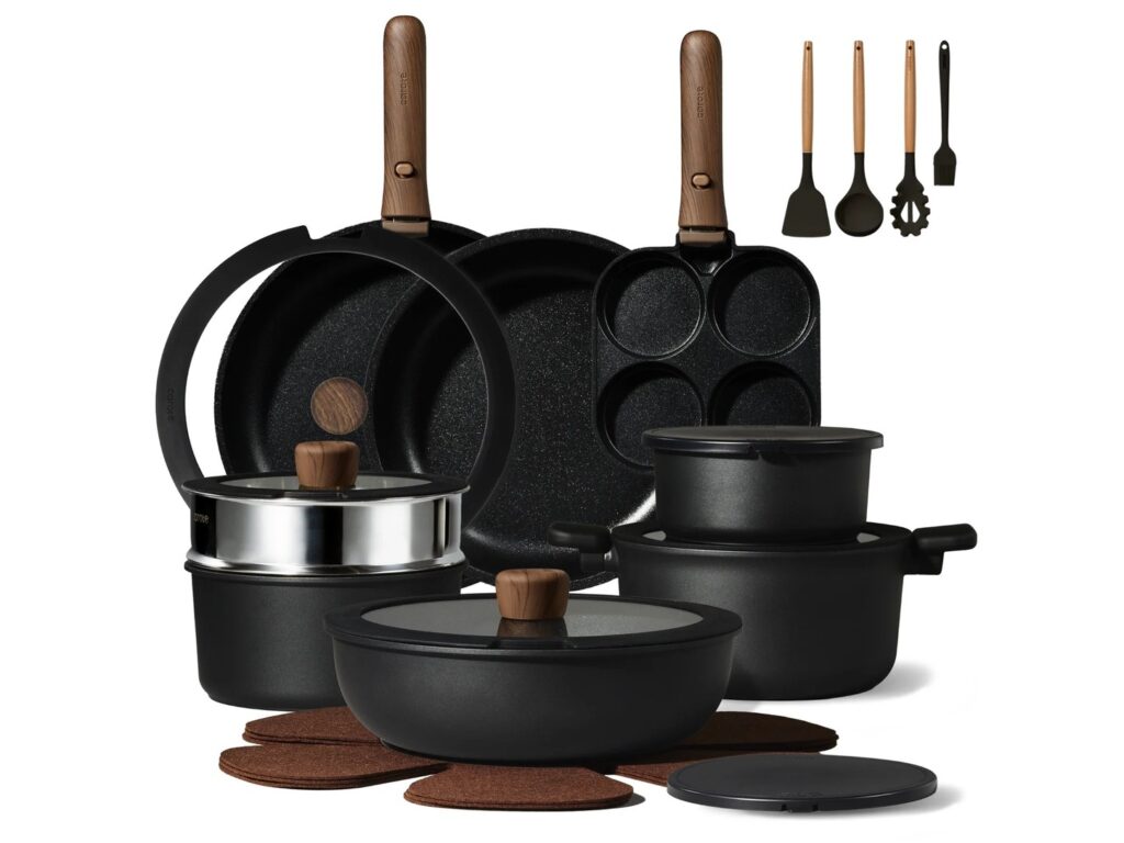 Complete CAROTE Forest cookware collection with dark vessels and wood-look handles in a dark kitchen setting