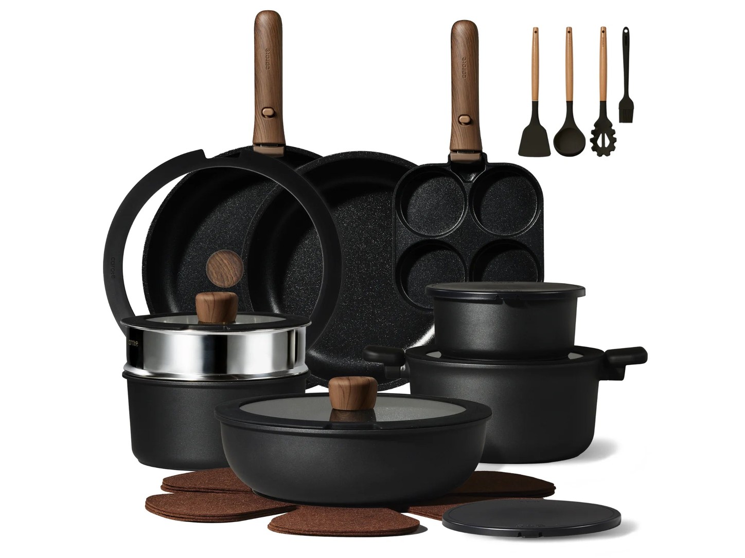 Complete CAROTE Forest cookware collection with dark vessels and wood-look handles in a dark kitchen setting