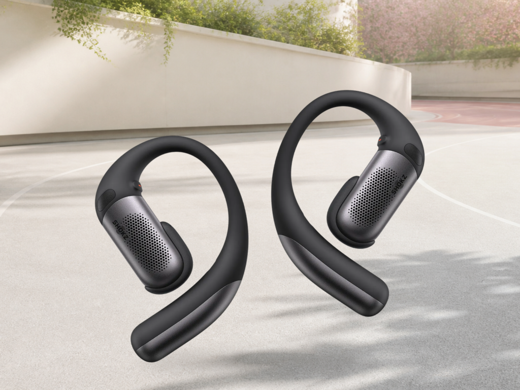 Official black Shokz OpenFit Pro open-ear earbuds shown complete on a warm mineral background