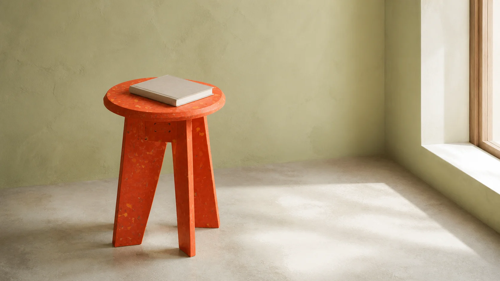 Orange BENTU “#” stool and side table with a closed book in a sunlit interior