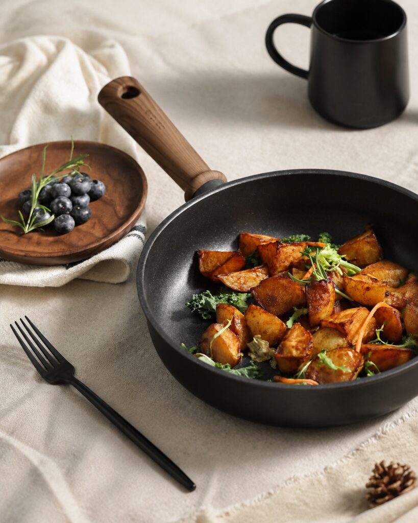 CAROTE Hokkaido black frying pan with wood-look handle in a warm dining scene