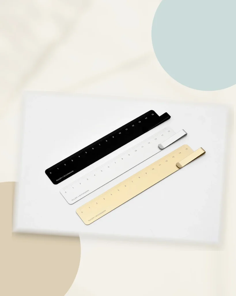 Black, silver and gold KACO RUMA 15cm aluminium ruler bookmarks arranged on a warm neutral editorial background