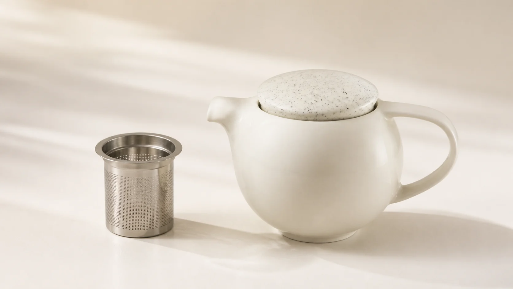 Loveramics Pro Tea 400ml ivory porcelain teapot with its removable stainless-steel infuser in a wide editorial rendering