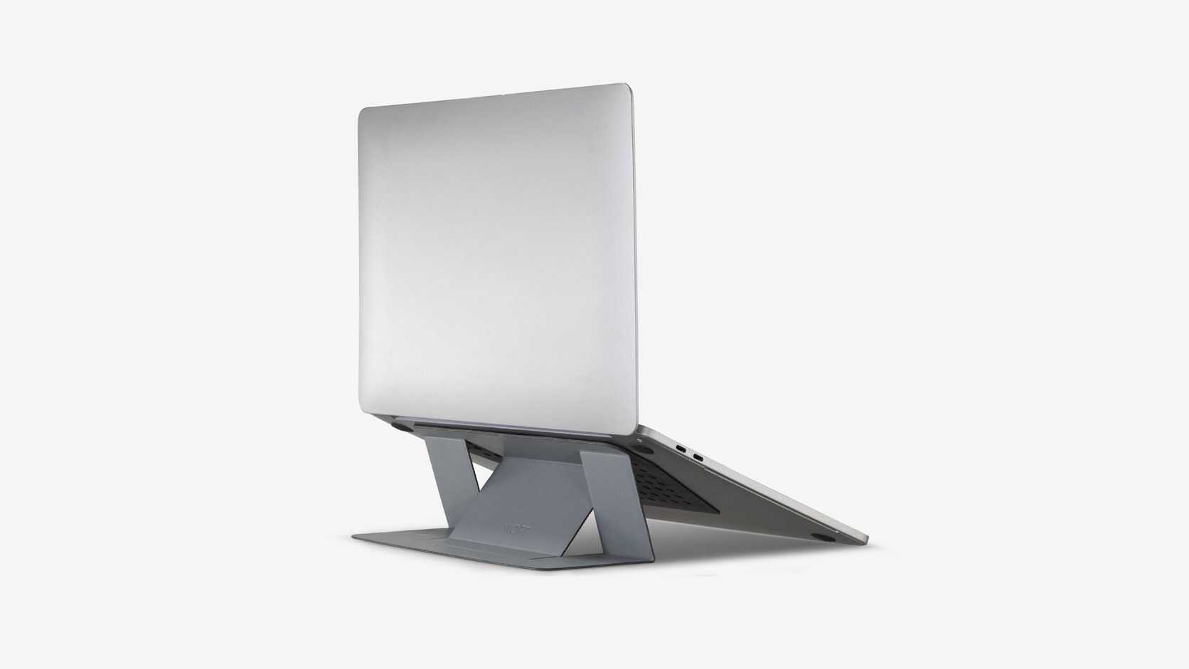 Wide view of the complete MOFT Adhesive Laptop Stand supporting a laptop on a clean neutral background