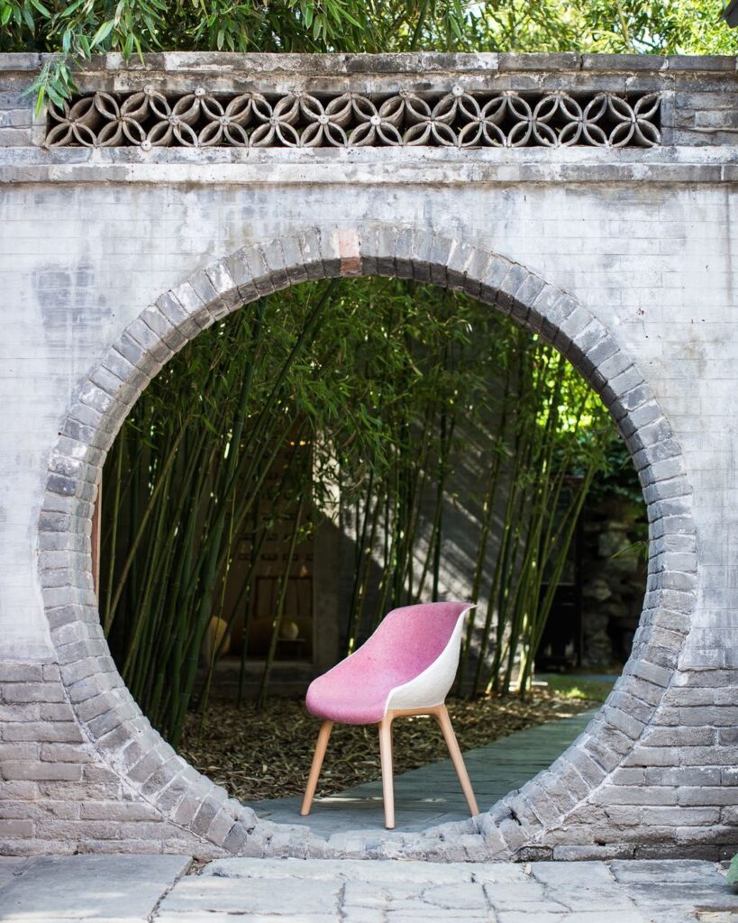 Pink PINWU GU paper-pulp chair framed by a circular garden opening