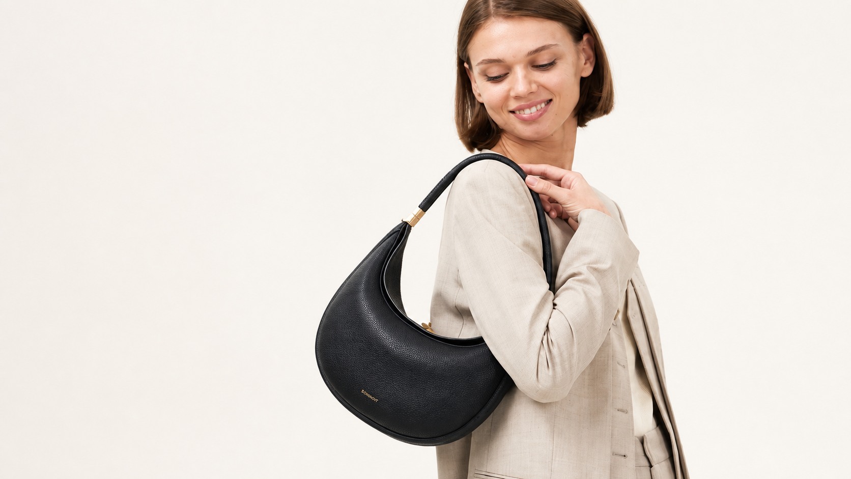 Songmont Luna Bag carried on the shoulder with its curved silhouette visible